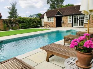 a swimming pool with a wooden bench and pink flowers at The Lakehouse Apartment by inspirestays-com in Rudgwick