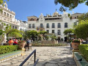 people sitting in chairs in front of a building at Casa Elegante Casares Costa Golf in Casares