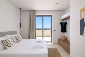 a white bedroom with a large bed and a window at Massari Hills Villa 9 in Malona Village