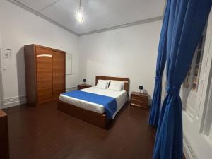 a bedroom with a bed and a blue curtain at Casa Senhor da Pedra in Vila Franca do Campo