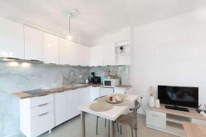 eine Küche mit weißen Schränken, einem Tisch und einem TV in der Unterkunft Sunset Sea View Cottage in Chalkidiki's Oasis in Metókhion Patriotikón