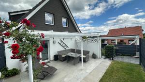 a patio with a table and a white pergola at Ferienhaus Achterhus für Familien & Homeoffice in Ratekau