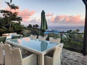 a patio with a table and chairs and an umbrella at La Villa Des Oliviers chambres d hôtes in Petite Île