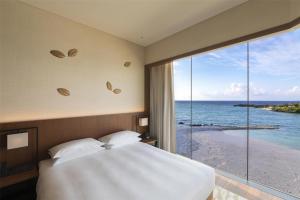 a bedroom with a bed and a view of the ocean at Hyatt Regency Seragaki Island Okinawa in Onna