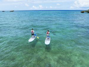 two people are standing on surfboards in the water at Hyatt Regency Seragaki Island Okinawa in Onna
