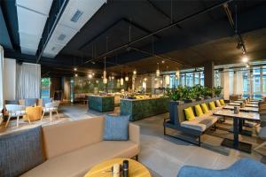 a restaurant with couches and tables and chairs at Flightgate Munich Airport Hotel, a member of Radisson Individuals in Hallbergmoos