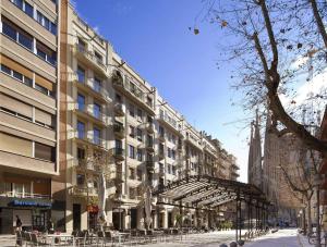 a large building with tables and chairs in front of it at Enjoybcn Gaudi Apartments in Barcelona