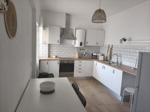 a kitchen with white cabinets and a table with chairs at RosaBela in Odiáxere +3 photos