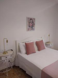 a white bed with two pink pillows in a bedroom at RosaBela in Odiáxere