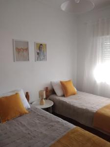 a bedroom with two beds and a table and a window at RosaBela in Odiáxere