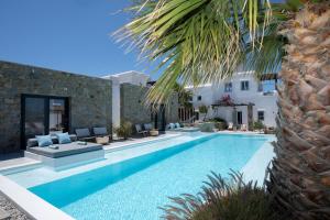 a swimming pool with chairs and a house at Myconian Theros Luxury Suites in Ano Mera