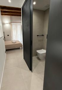 a bathroom with a toilet and a room with a bed at Aria Suites Cefalù in Cefalù