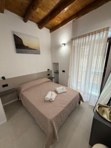 a bedroom with a bed with two towels on it at Aria Suites Cefalù in Cefalù