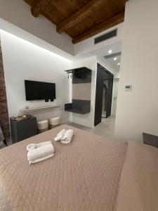 a bedroom with a bed with two towels and a flat screen tv at Aria Suites Cefalù in Cefalù