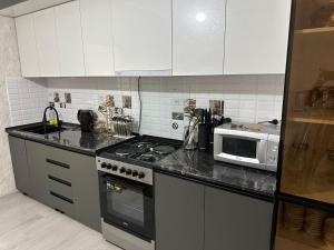 a kitchen with a stove and a microwave at Guest House NAZIRA in Kazarman