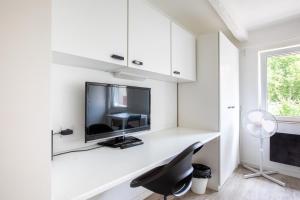 a white room with a desk with a tv and a chair at DeLuxe Studio Lumineux et Rénové, Parking Gratuit, MULHOUSE CENTRE in Mulhouse