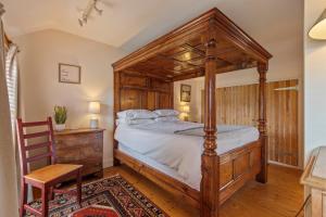 a bedroom with a wooden canopy bed and a chair at The Old Cottage - Central Location Near the Beach in Saundersfoot