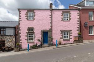 a pink house with a blue door on a street at The Old Cottage - Central Location Near the Beach in Saundersfoot