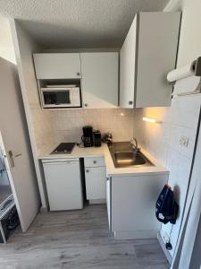 a small kitchen with white cabinets and a sink at Appartement centre-ville climatisé in Cavalaire-sur-Mer