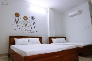 two beds in a room with white walls at Homestay Dream in Tuy Hoa