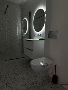 Un baño con inodoro, lavabo y espejo. en HAMORA AXXIS Mamaia, en Mamaia
