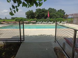 a swimming pool with a fence and a tennis court at Les Coquettes in Richerenches
