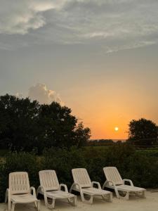 a group of four white chairs sitting in front of a sunset at Les Coquettes in Richerenches