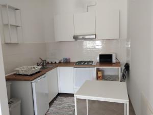 a small kitchen with white cabinets and a white table at Agorà 1 in Parghelia