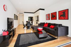 uma sala de estar com um sofá preto e almofadas vermelhas em New York on Riley - Split-Level Executive 2BR Darlinghurst Apartment with a New York Feel em Sydney