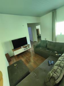 a living room with a couch and a flat screen tv at Casa com dois quartos e piscina in Barreirinhas
