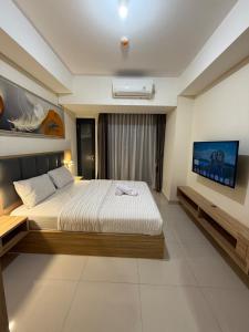 a bedroom with a bed and a tv on the wall at Pollux studio Suite 2 by Superstay in Batam Center