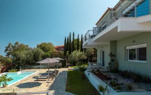 a house with a swimming pool and an umbrella at Dimelli Luxury Suites in Ermioni