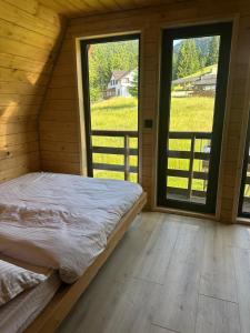 een bed in een kamer met 2 grote ramen bij Rivera Cabin in Colibiţa