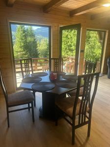 een eetkamer met een tafel, stoelen en ramen bij Rivera Cabin in Colibiţa