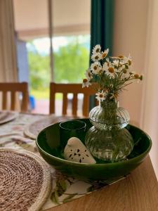Un plato verde con un jarrón con flores sobre una mesa. en Apartament Magia Puszczy z widokiem na Puszcze Białowieska, en Hajnówka