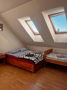 a attic bedroom with two beds and two windows at MAGURA in Pszczeliny