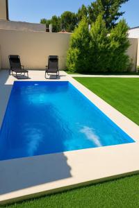 a blue swimming pool with two chairs in a yard at Chalet con pileta y quincho, hermoso jardín in Tandil
