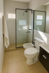 a bathroom with a toilet and a glass shower at Chalet con pileta y quincho, hermoso jardín in Tandil +2 photos