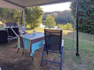 a table and a chair under a tent at Le petit bonheur caravan met voortent en buitenkeuken in Maisonnais-sur-Tardoire