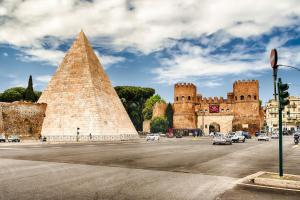 ein Gebäude mit einer Pyramide und Autos in einer Straße in der Unterkunft Tanner's Apartment - Piramide in Rom
