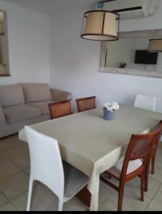 a dining room table with chairs and a couch at Chalet con pileta y quincho, hermoso jardín in Tandil