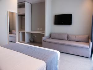 a room with a bed and a couch and a tv at Dukes Albania in Vlorë