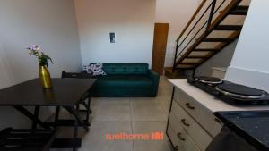 ein Wohnzimmer mit einer grünen Couch und einem Tisch in der Unterkunft Loft em Ponta Grossa com Excelente Localizacao in Ponta Grossa