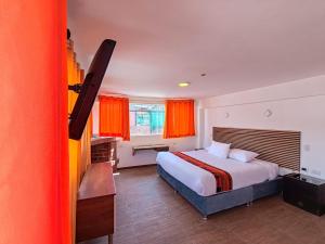 una camera da letto con un grande letto con tende arancioni di Hotel Cusco Museo a Cuzco