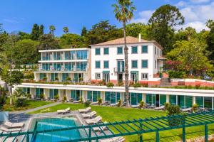 an exterior view of a large white building with a swimming pool at Pestana Quinta Perestrello in Funchal