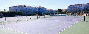 a tennis court with buildings in the background at Casa Saudade - Oasis Parque Country Club in Portimão