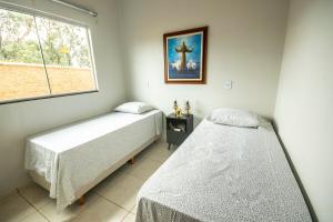 two beds in a room with a window at Recanto das Araras in Pirenópolis