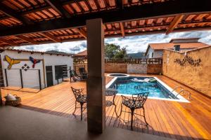 a patio with a pool and chairs on a wooden deck at Recanto das Araras in Pirenópolis