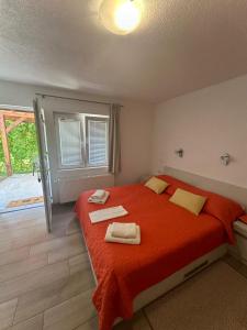 a bedroom with a red bed with two towels on it at Guest house Ema in Grabovac