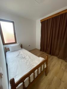 a bedroom with a bed with white sheets and a window at Meshkoski Apartments in Peštani
